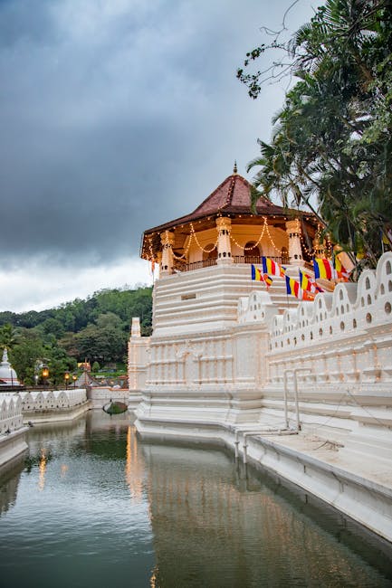 Beautiful view of a sacred temple reflecting in the river, surrounded by lush greenery, under a moody sky in Sri Lanka.