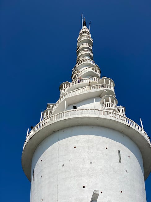 Vertical shot of the Ambuluwawa Tower in Sri Lanka against a vibrant blue sky, showcasing its unique architecture.