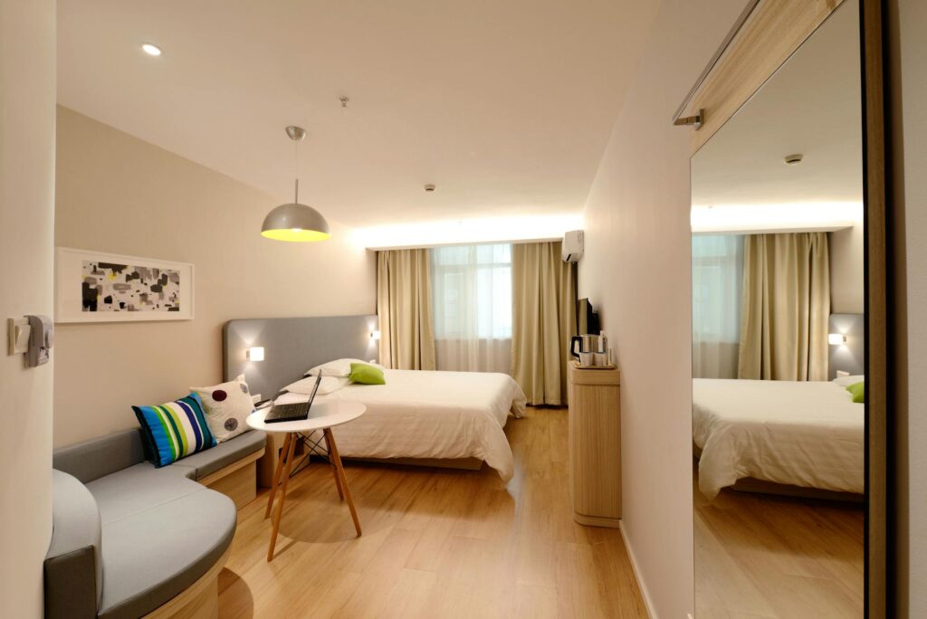 Spacious modern hotel room featuring cozy decor and neutral tones with natural light.